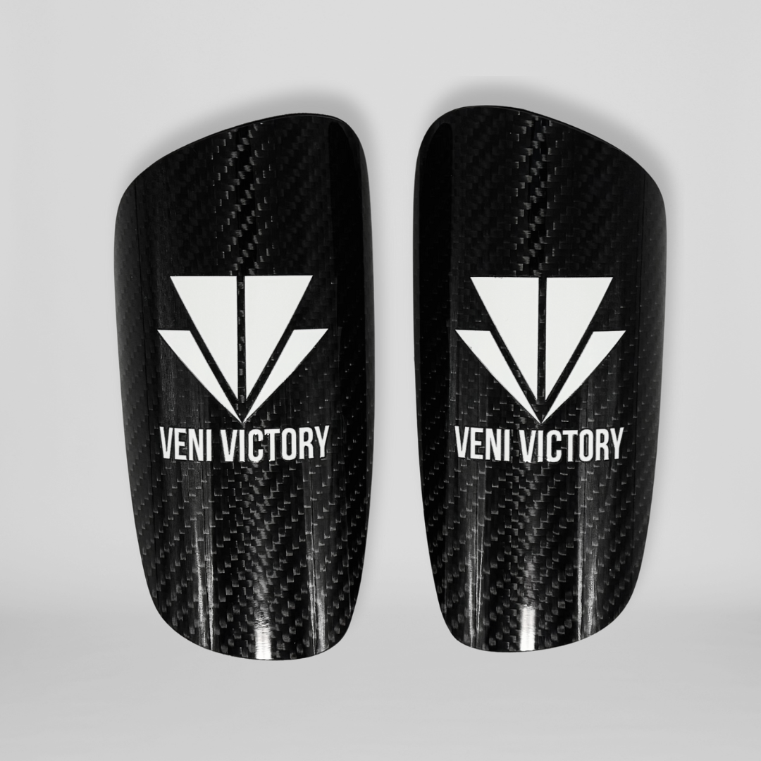 Leichte und robuste Schienbeinschoner Pro / gross aus Carbon in Schwarz mit weissem VENI VICTORY Logo, bieten optimalen Schutz und Komfort für Fußballspieler.